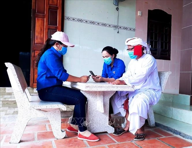 Đoàn viên, thanh niên Ninh Thuận hướng dẫn người dân cài đặt ứng dụng Bluezone trên điện thoại thông minh. Ảnh: Công Thử - TTXVN