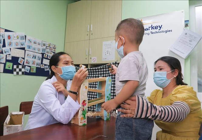 Một phụ huynh tham gia vào quá trình can thiệp cho trẻ tự kỷ . Ảnh: Đinh Hằng – TTXVN.
