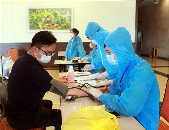 Nhân viên y tế hướng dẫn chuyên gia, lao động nước ngoài khai báo y tế và kiểm tra sức khỏe trước khi vào khách sạn cách ly. Ảnh: Đồng Thúy-TTXVN