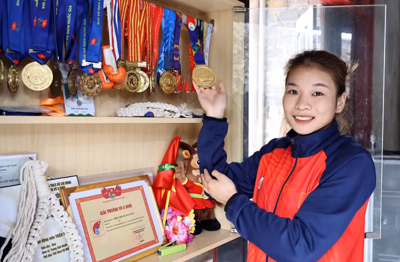 Vận động viên Triệu Thị Phương Thủy bên tủ huy chương các loại mà cô đã giành được. Ảnh: Trung Kiên - TTXVN
