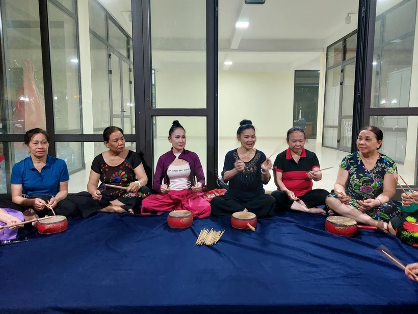 Nghệ nhân Minh Tám (thứ 3 từ phải sang) truyền dạy trống hội cho mọi người. Ảnh: Đinh Thuận - TTXVN