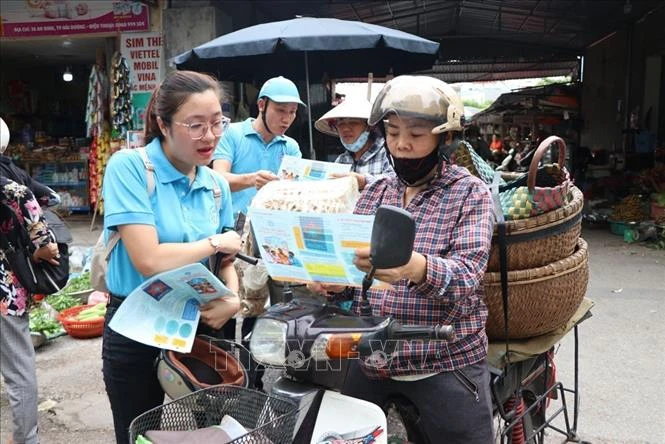 Tuyên truyền và hướng dẫn người dân tham gia bảo hiểm xã hội tự nguyện, bảo hiểm y tế hộ gia đình tại chợ . Ảnh: Mạnh Minh- TTXVN