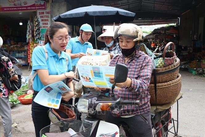 Tuyên truyền và hướng dẫn người dân tham gia bảo hiểm xã hội tự nguyện, bảo hiểm y tế hộ gia đình tại chợ . Ảnh: Mạnh Minh- TTXVN