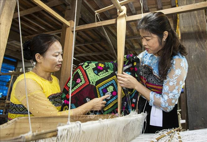 Chị Vì Thị Oanh (áo xanh), Phó Chủ nhiệm Hợp tác xã dệt thổ cẩm và dịch vụ du lịch Chiềng Châu chia sẻ kinh nghiệm cho các hội viên. Ảnh: Trọng Đạt - TTXVN 