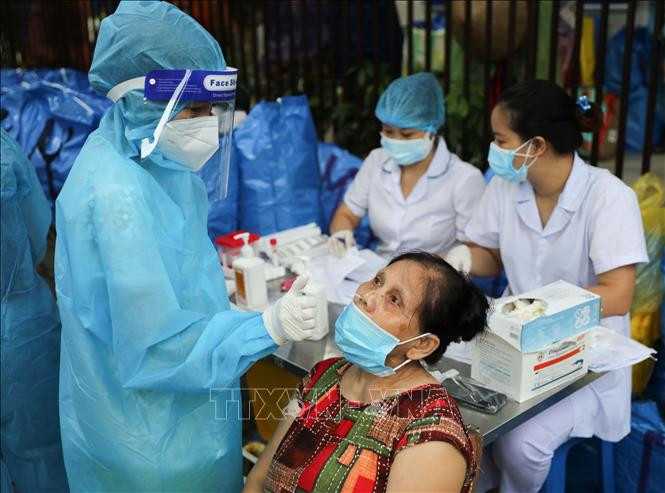 Lấy mẫu test nhanh cho người dân đến nhận quà hỗ trợ tại "Chợ nhân đạo". Ảnh: Thanh Tùng -TTXVN 