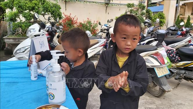 Hai học sinh lớp 1 thực hiện rửa tay sát khuẩn trước khi vào dự lễ khai giảng. Ảnh: Nguyễn Chiến - TTXVN