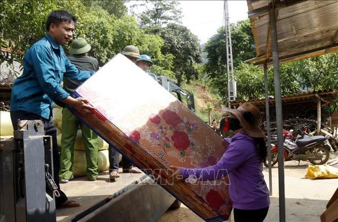 Lực lượng chức năng giúp các hộ dân trong khu vực bị sạt lở đất di dời tài sản. Ảnh: Quốc Khánh - TTXVN