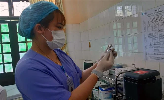 Kiểm tra vaccine phòng COVID-19 trước khi tiêm. Ảnh: Nguyễn Chinh - TTXVN 