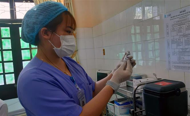 Kiểm tra vaccine phòng COVID-19 trước khi tiêm. Ảnh: Nguyễn Chinh - TTXVN 