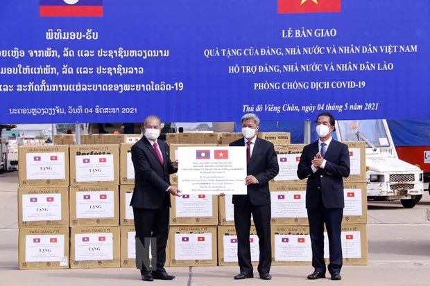 Thứ trưởng Bộ Y tế Nguyễn Trường Sơn đang trao tượng trưng 2 triệu khẩu trang y tế và 200 máy thở và các vật tư y tế là quà tặng của Đảng, Nhà nước và nhân dân Việt Nam dành cho Đảng, Nhà nước và nhân dân Lào trong công tác phòng chống COVID-19. Ảnh: Phạm