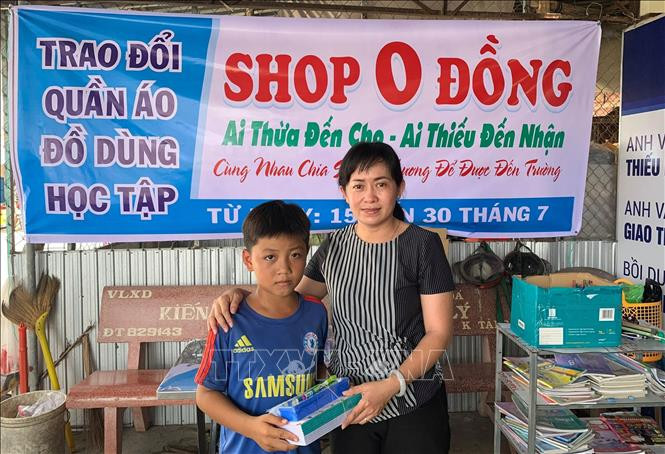 Cô Lê Thị Anh Đào tặng tập vở, đồ dùng học tập cho học sinh nghèo. Ảnh: Lê Sen - TTXVN