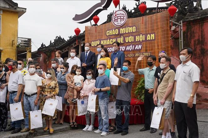 Chính quyền thành phố Hội An tặng quà lưu niệm cho các đoàn khách quốc tế đầu tiên đến tham quan phố cổ Hội An vào ngày 20/11 theo chương trình du lịch "Hộ chiếu vaccine" sau 2 năm bị gián đoạn do đại dịch COVID-19. Ảnh: Đoàn Hữu Trung - TTXVN