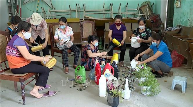 Người dân tận dụng các loại chai nhựa để làm chậu trồng hoa. Ảnh: TTXVN phát 