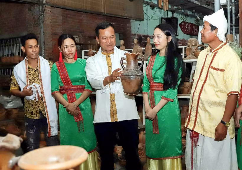 Anh Đàng Chí Quyết giới thiệu với du khách về gốm truyền thống của làng nghề. Ảnh: TTXVN phát 