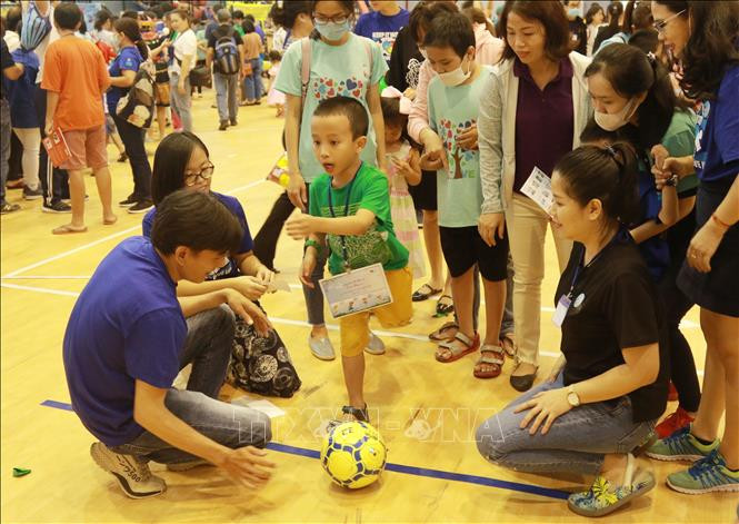 Các chuyên viên can thiệp hướng dẫn trẻ tự kỷ chơi bóng đá. Ảnh: Đinh Hằng - TTXVN