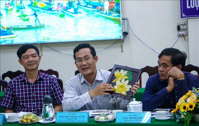Hội đồng đánh giá, xếp hạng sản phẩm OCOP thành phố Cần Thơ nhận xét sản phẩm tranh gạo của tác giả Khưu Tấn Bửu. Ảnh: Thanh Liêm - TTXVN