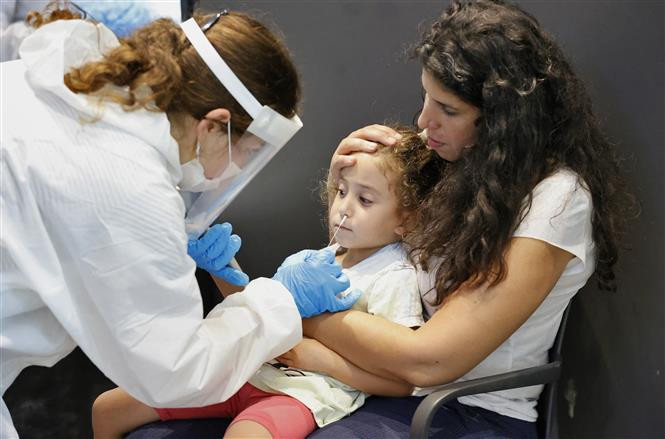 Nhân viên y tế lấy mẫu xét nghiệm COVID-19 cho một em nhỏ tại thành phố Tel Aviv, Israel. Ảnh: AFP/TTXVN 