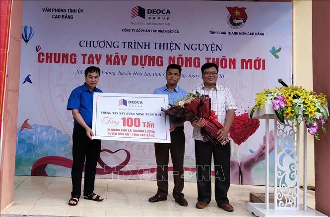 Đại diện Công ty cổ phần tập đoàn Đèo cả tặng xi măng hỗ trợ nhân dân xã Trương Lương, Hòa An, Cao Bằng làm đường giao thông nông thôn. Ảnh: Quốc Đạt - TTXVN