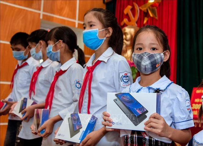 Các em học sinh huyện Ba Vì nhận những chiếc máy tính bảng từ các nhà hảo tâm. Ảnh: Trần Việt - TTXVN 