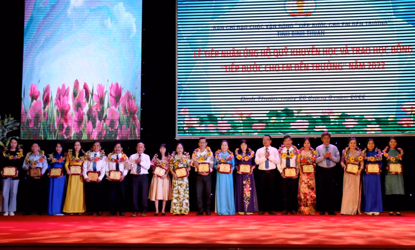 Tặng biểu trưng và hoa cho các đơn vị ủng hộ cho Quỹ học bổng “Tiếp bước cho em đến trường”. Ảnh: Nguyễn Thanh – TTXVN 