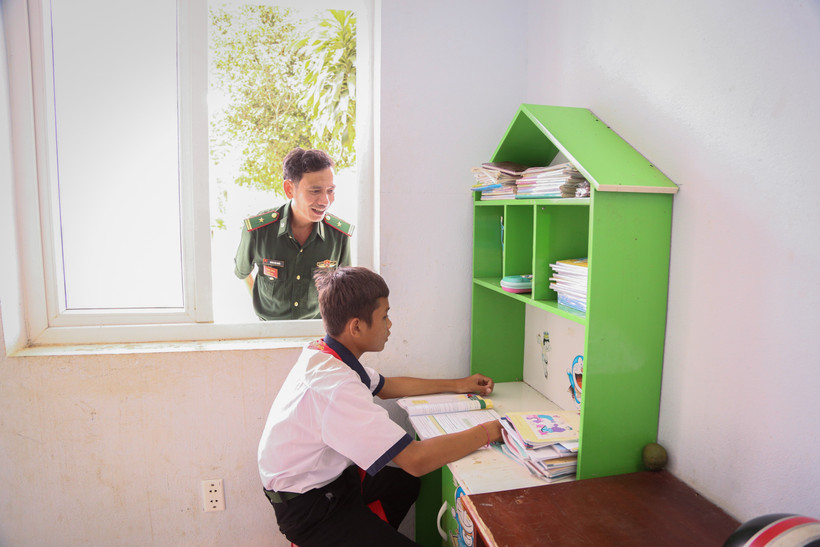 Thiếu tá Huỳnh Tấn Thuần, Đồn Biên phòng Kà Tum theo dõi việc học tập tại đồn của em Hố Chanh Đi, dân tộc Khmer, học sinh lớp 8, trường THCS Tân Đông, huyện Tân Châu. Ảnh: Giang Phương – TTXVN