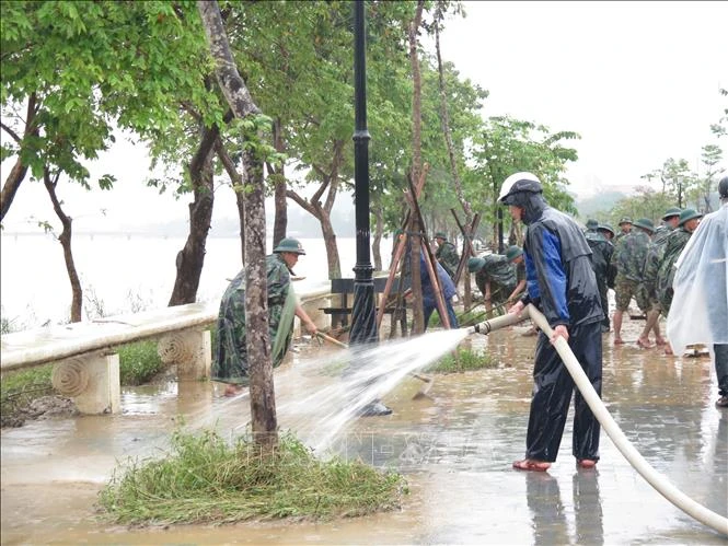 Các lực lượng dọn dẹp bùn đất tại khu vực 2 bên bờ sông Hương. Ảnh: Tường Vi - TTXVN
