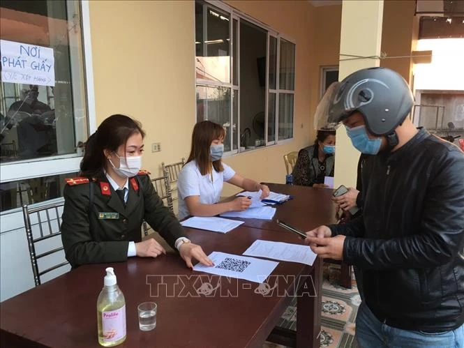 Hướng dẫn công dân khai báo y tế điện tử tại các chốt kiểm soát dịch bệnh COVID-19. Ảnh: TTXVN phát