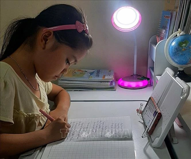 Nhiều gia đình khó khăn trong việc mua máy tính trong khi học sinh học trực tuyến trên điện thoại . Ảnh: TTXVN phát 
