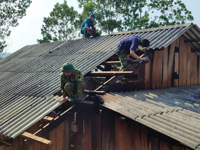 Lực lượng chức năng hỗ trợ người dân sửa chữa căn nhà bị tốc mái do dông lốc, mưa đá. Ảnh: TTXVN phát
