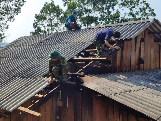 Lực lượng chức năng hỗ trợ người dân sửa chữa căn nhà bị tốc mái do dông lốc, mưa đá. Ảnh: TTXVN phát
