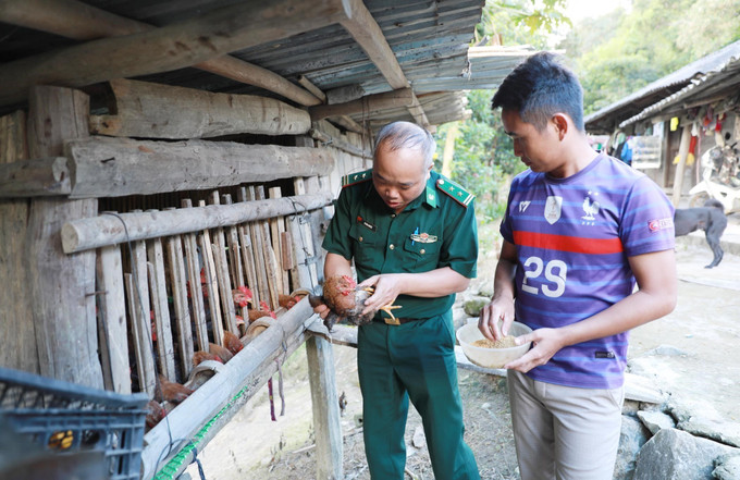 Cán bộ Đội vận động quần chúng Đồn Biên phòng Pa Tần hướng dẫn người dân cách chăm sóc đàn vật nuôi.