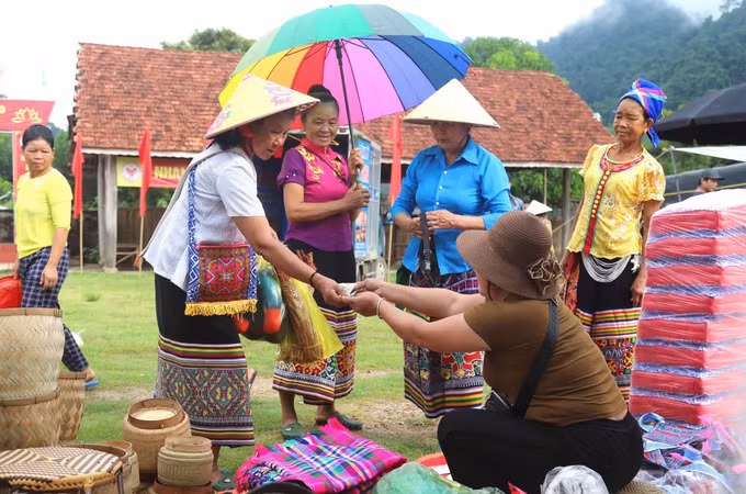 Các bà, mẹ người dân tộc Thái lựa chọn, mua sản phẩm đồng dùng cho sinh hoạt gia đình tại khu vực chuyên bán các sản phẩm truyền thống của đồng bào dân tộc Thái. Ảnh: Xuân Tiến/TTXVN