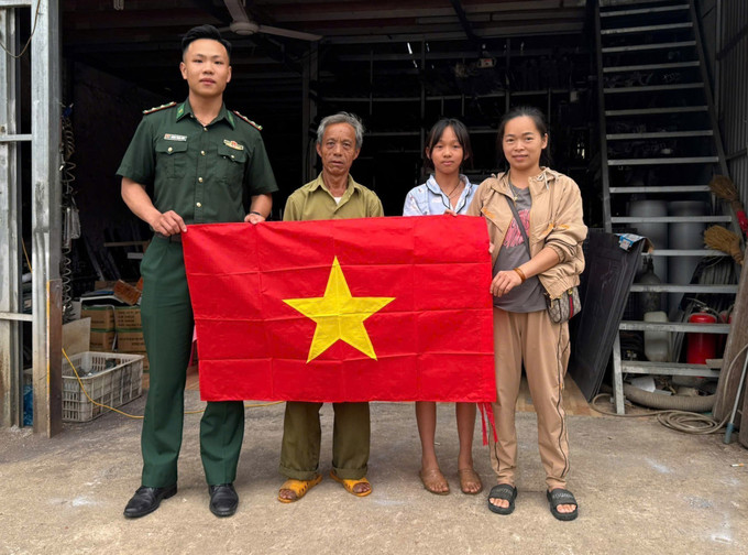 Trung úy Hoàng Trung Kiên tặng cờ Tổ quốc cho đồng bào khu vực biên giới.