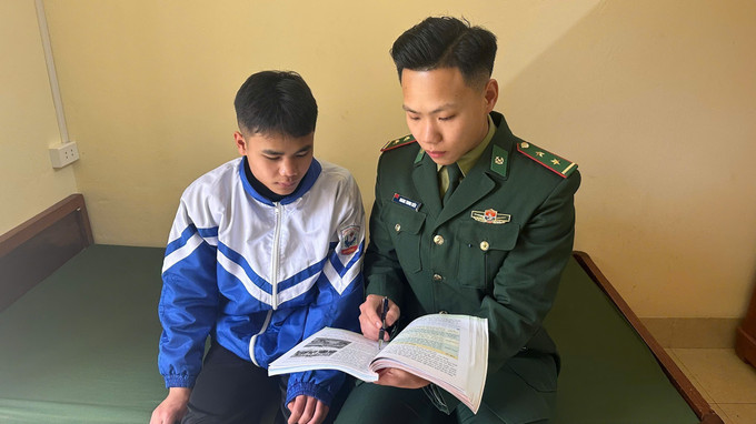 Trung úy Hoàng Trung Kiên hướng dẫn con nuôi Đồn biên phòng làm bài tập.