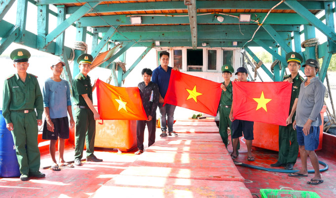 BĐBP Cà Mau tuyên truyền và tặng cờ cho ngư dân vươn khơi bám biển. Ảnh: TTXVN phát