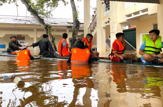 Cán bộ, chiến sĩ Bộ Chỉ huy Quân sự tỉnh Tuyên Quang đưa các học sinh ra khỏi điểm trường bị ngập sâu. Ảnh: Đăng Ninh/TTXVN phát