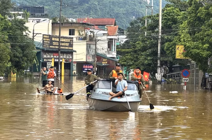 Cán bộ, chiến sĩ Công an tỉnh Tuyên Quang hỗ trợ người dân phường Hà Giang 1 sơ tán khu vực ngập lụt. Ảnh: Minh Tâm/TTXVN