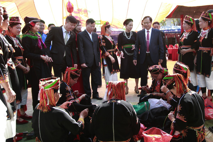 Lãnh đạo xã Vĩnh Tuy và các đại biểu tham quan phụ nữ dân tộc Dao trình diễn nghề thêu trong khu trải nghiệm văn hóa - số tại Hội chợ số.