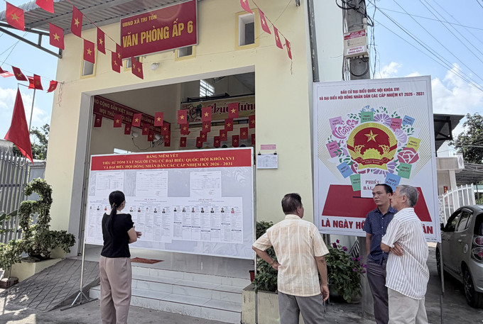 Cử tri theo dõi bảng niêm yết danh sách ứng cử viên và pa nô cổ động ngày bầu cử tại Văn phòng ấp 6, xã Tri Tôn, An Giang.
