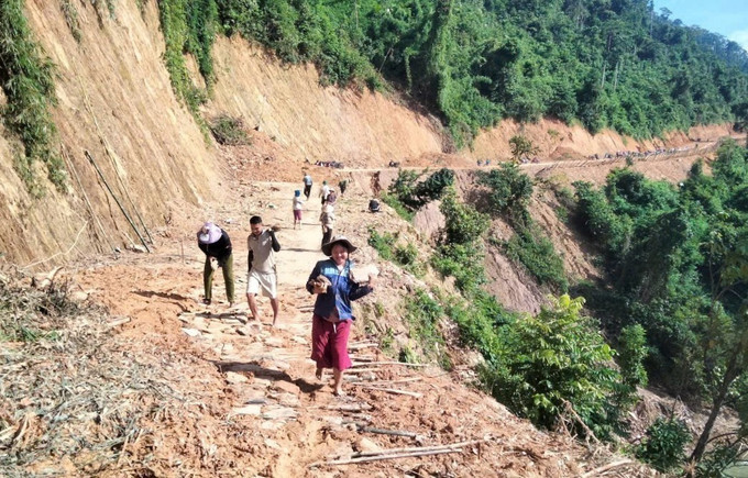 Người dân khuân vác đá để xếp mặt đường hiện đang bị phủ lớp bùn nhão, sình lầy tại các điểm sạt lở. Ảnh: TTXVN phát Người dân khuân vác đá để xếp mặt đường hiện đang bị phủ lớp bùn nhão, sình lầy tại các điểm sạt lở. Ảnh: TTXVN phát