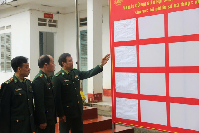 Cán bộ, chiến sỹ Đồn Biên phòng Bản Lầu kiểm tra thông tin danh sách cử tri được niêm yết tại khu vực bỏ phiếu số 3 xã Bản Lầu. Ảnh: Hương Thu/TTXVN
