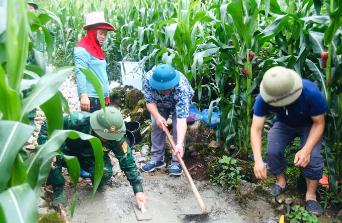 Cán bộ, chiến sĩ Đồn Biên phòng Tùng Vài cùng người dân địa phương tham gia đổ bê tông tuyến đường tại thôn Chín Sang, xã Tùng Vài (Tuyên Quang). Ảnh: Hoàng Chính/TTXVN phát