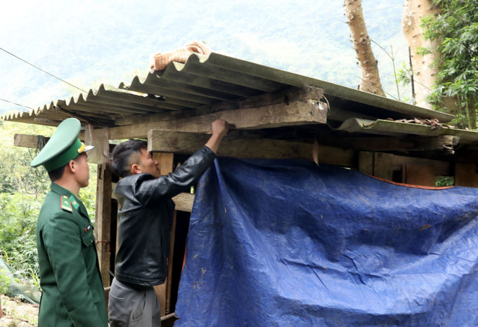 Chiến sĩ Đồn biên phòng Cửa khẩu quốc tế Nậm Cắn (Nghệ An) hướng dẫn người dân bản Trường Sơn, xã Nậm Cắn che chắn chuồng trại cho đàn trâu bò.