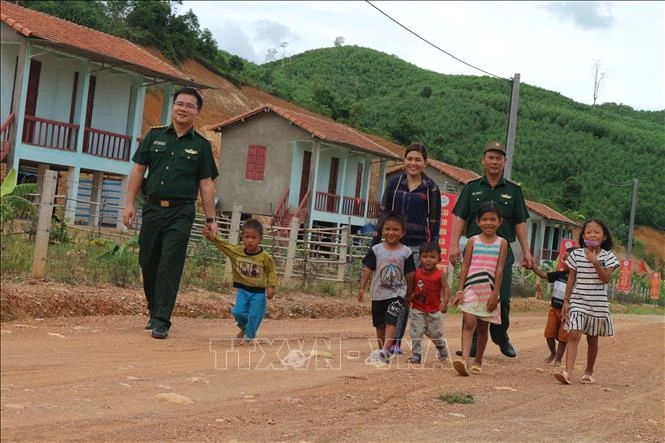 Bộ đội Biên phòng Hà Tĩnh và trưởng bản Hồ Thị Kiên vận động trẻ em trong bản đến trường. Ảnh: Hoàng Ngà - TTXVN