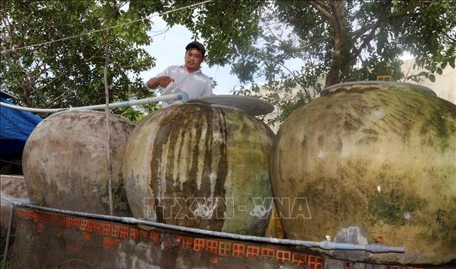 Tranh thủ vào mùa mưa, người dân sinh sống ven biển An Biên tận dụng lu để chứa nước sử dụng. Ảnh: Lê Sen - TTXVN