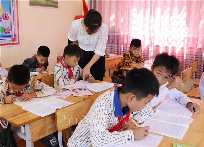 Giáo viên Trường Tiểu học Đoàn Kết, huyện Phong Thổ (Lai Châu) hướng dẫn học sinh viết chữ. Ảnh: Việt Hoàng-TTXVN 