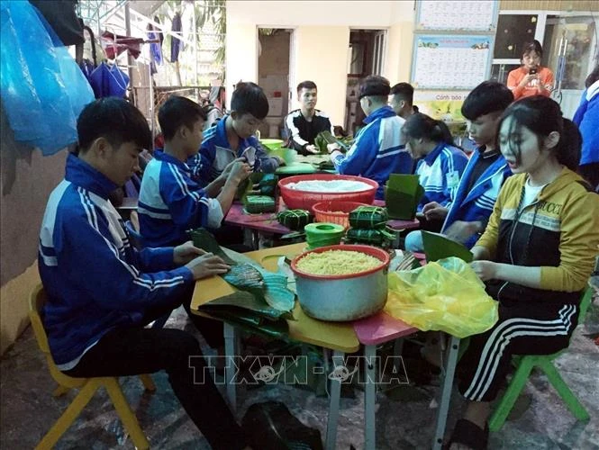 Các em Trường THPT Nguyễn Cảnh Chân, huyện Thanh Chương (Nghệ An) gói bánh chưng ủng hộ đồng bào bị ảnh hưởng bởi lũ lụt. Ảnh: TTXVN phát