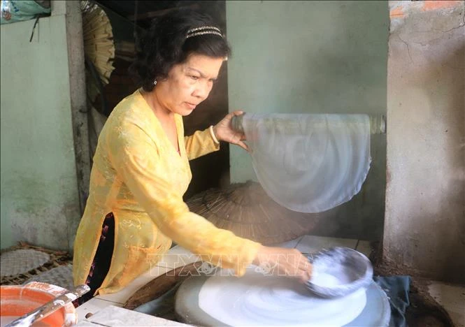 Bà Trần Thị Tuyết Mai, xã Lục Sĩ Thành, huyện Trà Ôn, tỉnh Vĩnh Long tỉ mỉ tráng từng chiếc bánh. Ảnh: Lê Thúy Hằng – TTXVN.