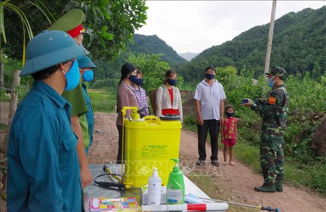 Lực lượng biên phòng tuyên truyền nâng cao nhận thức phòng chống dịch, phát khẩu trang miễn phí, sát khuẩn, kiểm tra y tế (đo thân nhiệt) cho người dân. Ảnh: Xuân Tiến-TTXVN 