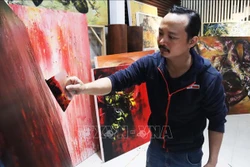 Họa sĩ Ngô Thanh Hùng sáng tác tranh tại nhà. Ảnh: Văn Dũng - TTXVN